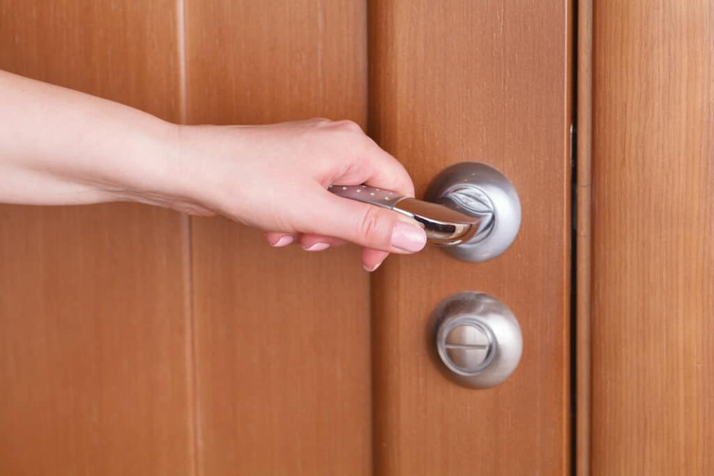 female hand hold handle of wood door