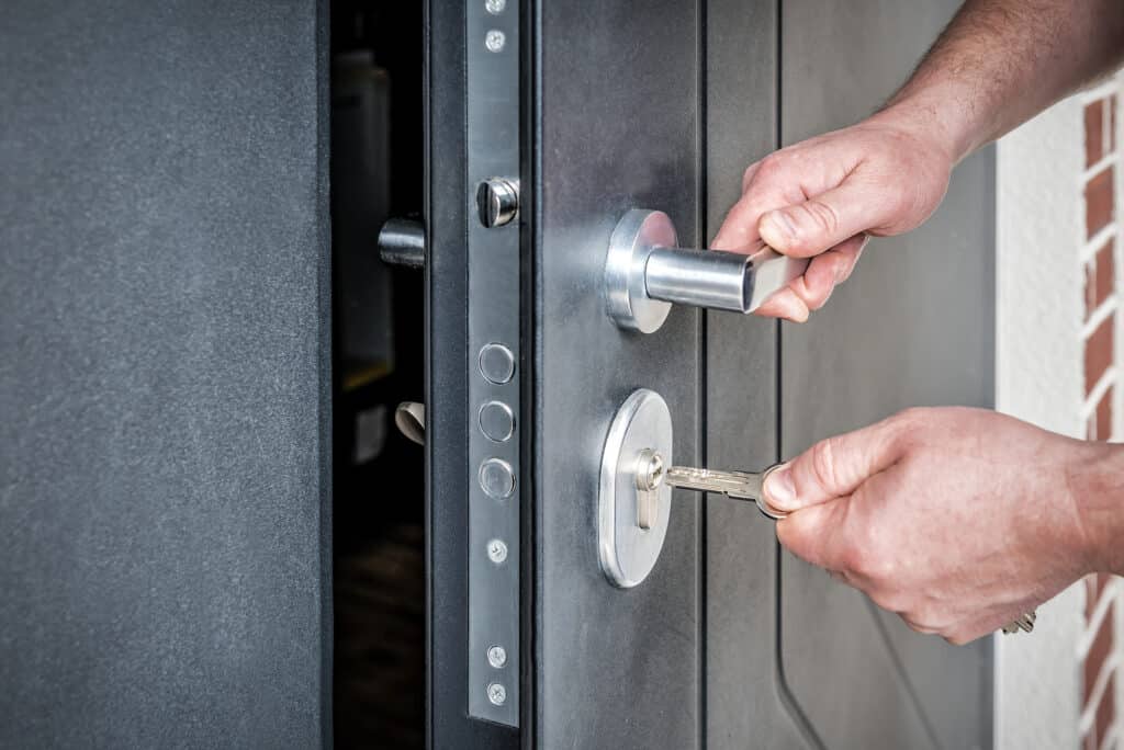 Hand putting house key into front door lock of new house