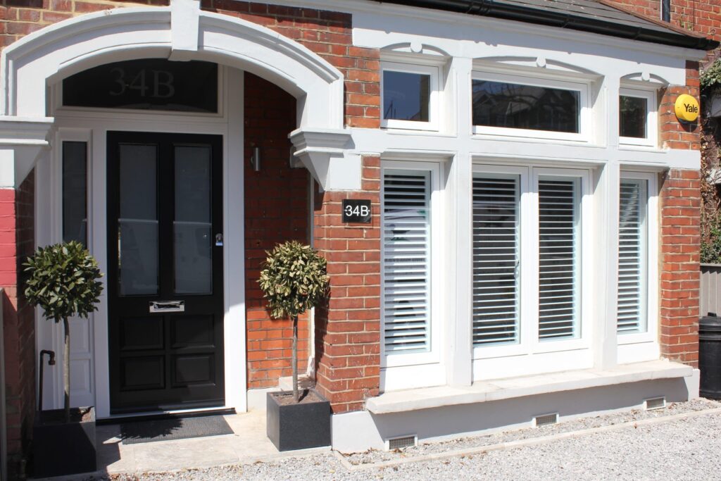 a black timber front door and a flush casement window
