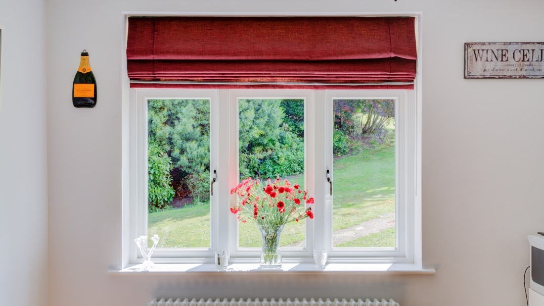 a upvc sash windows with red blind and flowers on the window sill