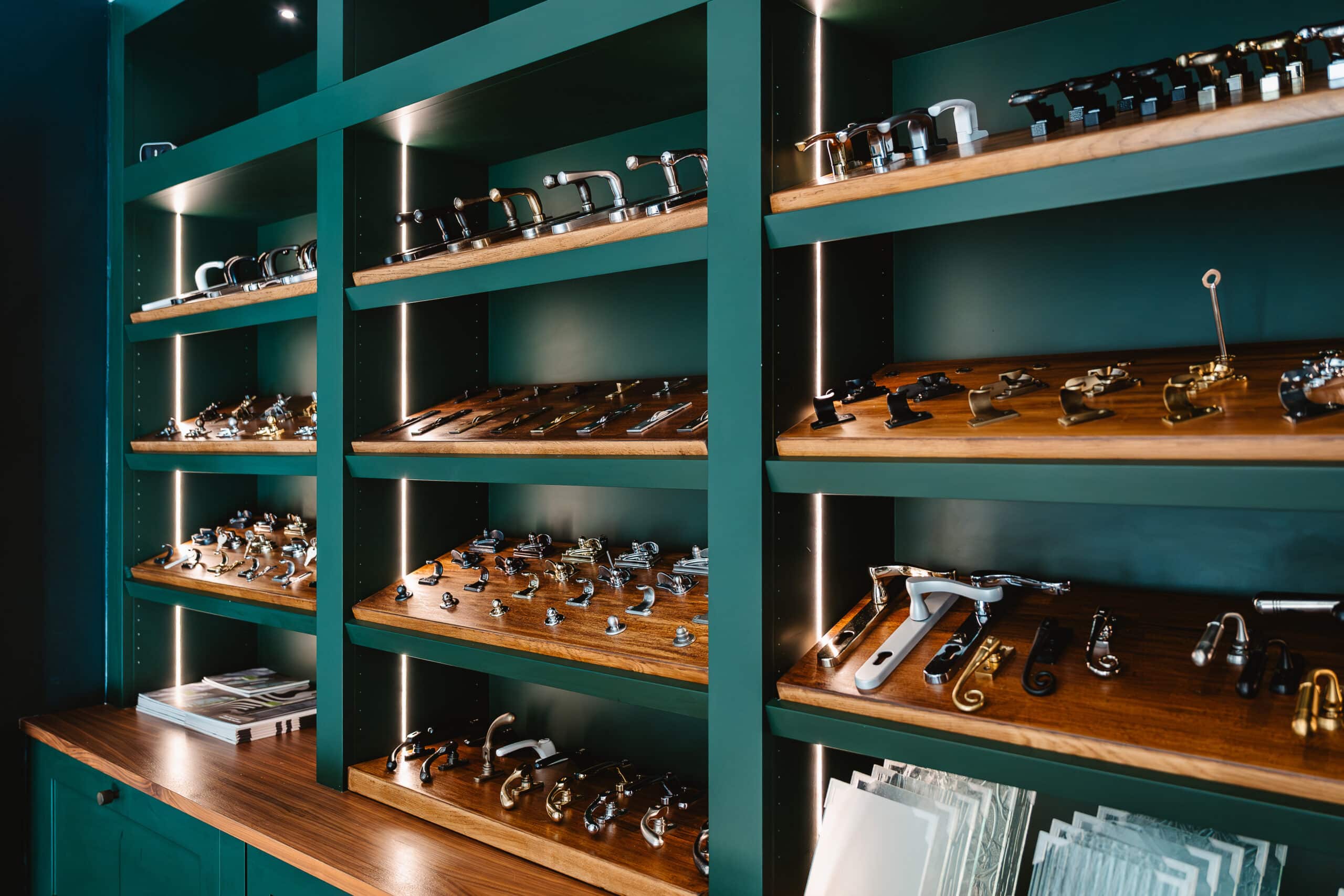 Dark green showroom shelves showing a variety of window and door accessories such as handles and locks